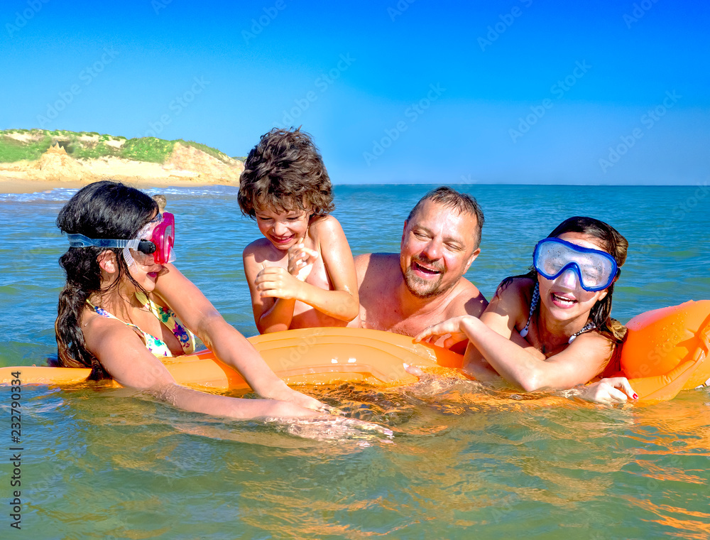 happy family with children is swimming and having fun in the sea on an inflatable mattress. happy friendly family concept happy family with children is swimming and having fun in the sea on an inflatable mattress. happy friendly family concept