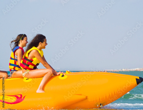 extreme speed attraction in the sea.ea attraction. Group of young enjoying a ride on a banana boat on sunny summer day. Beach water sport