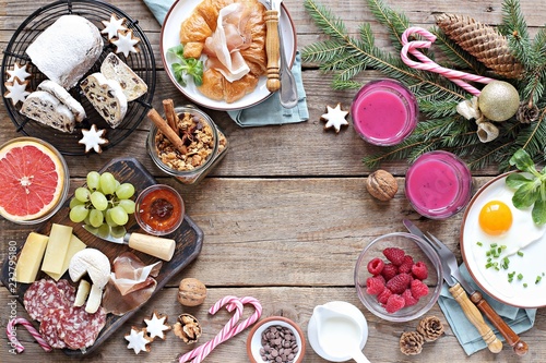 Christmas brunch or breakfast table. Festive brunch set, meal variety with fried egg, appetizers platter, croissant, granola, smoothy and traditional sweets . Overhead view