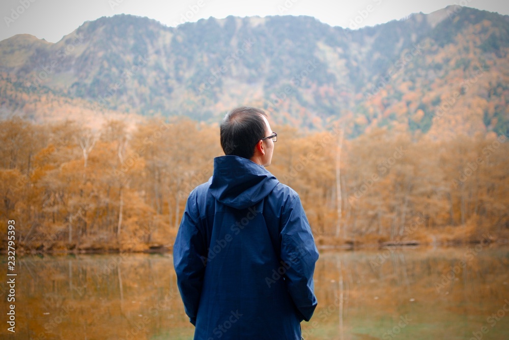 freedom man with stand near the lake side against natural autumn forest and mountains