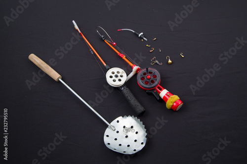 tackle for winter fishing. Fishing rods, bait, fishing line on a black background.