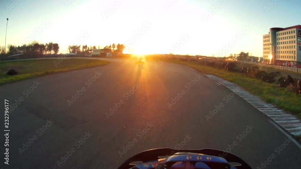 people drive karts on the track before sunset. The camera is installed helmet