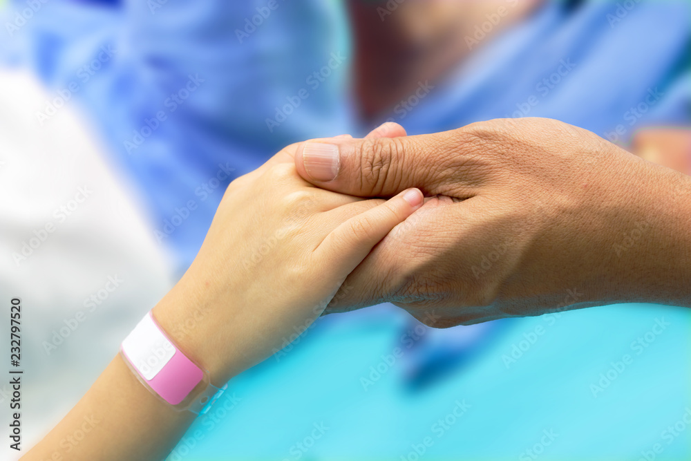 hand hold a child's patients hand with bracelet hand hold a child's patients hand with bracelet