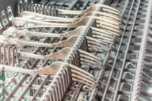 Silver forks lie in the upper compartment of the dishwasher © Evgenii