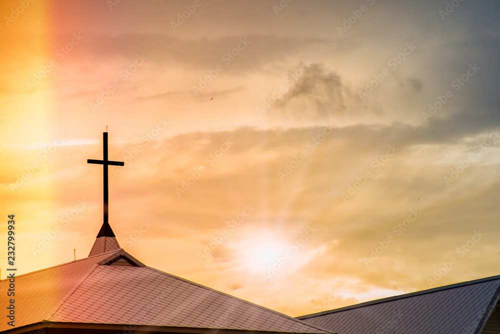 Holy Jesus cross on chapel roof with spiritual twilight sky and light leak background Holy Jesus cross on chapel roof with spiritual twilight sky and light leak background