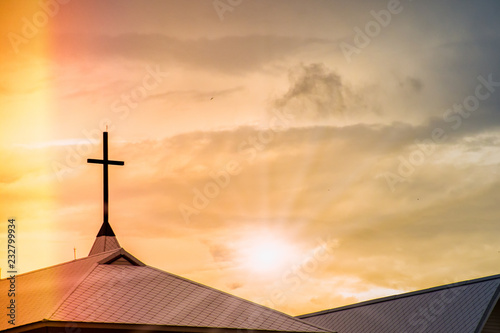 Holy Jesus cross on chapel roof with spiritual twilight sky and light leak background