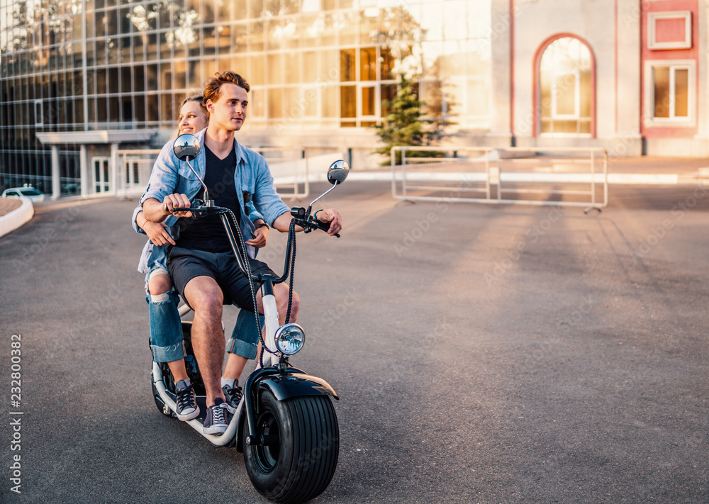 Lovely young couple driving electric bike during summer. Modern city dating and transportation