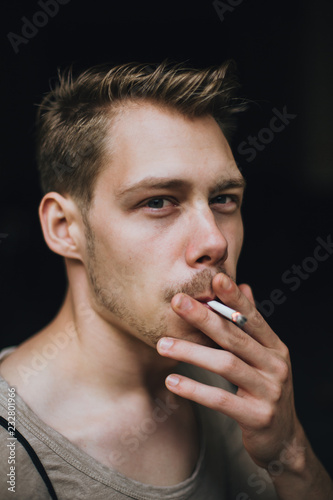 Gesicht eines jungen weißen Mannes, der an einer Zigarette zieht