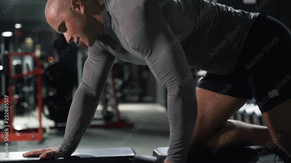 Close-up athlete in the gym with dumbbells performing exercises on the back muscles Close-up athlete in the gym with dumbbells performing exercises on the back muscles
