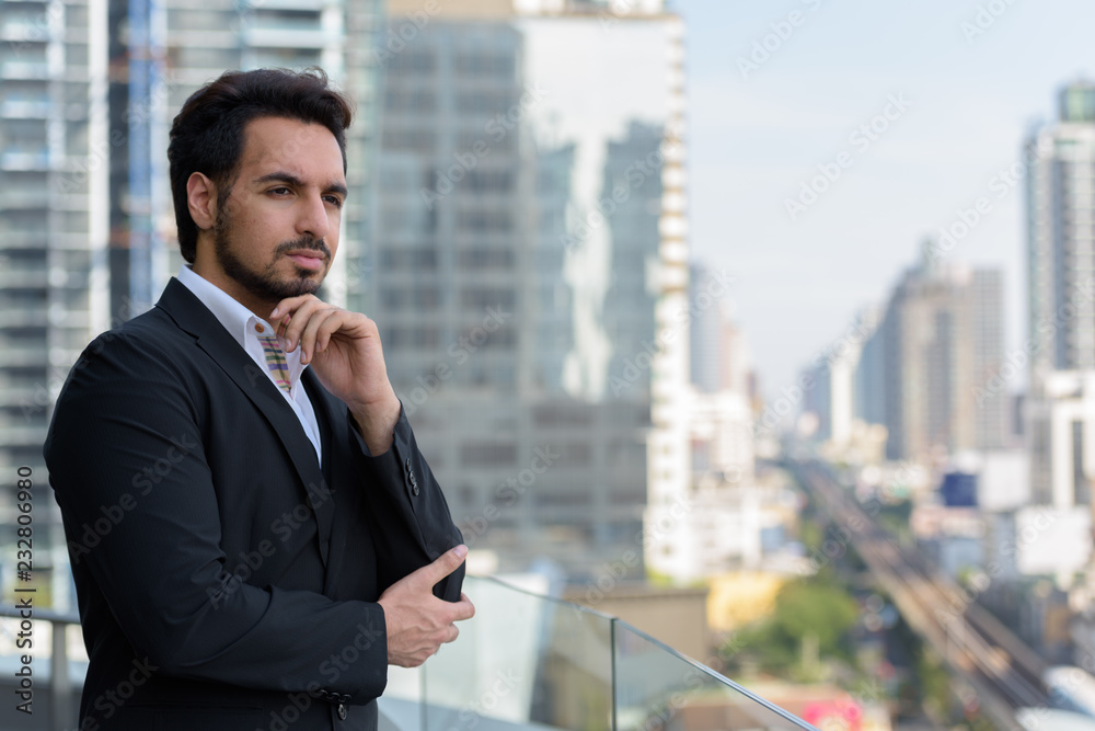 Young handsome Indian businessman thinking at rooftop in Bangkok Young handsome Indian businessman thinking at rooftop in Bangkok
