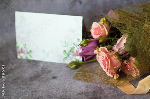 A beautiful bouquet of roses in a package with a postcard for text on a gray background