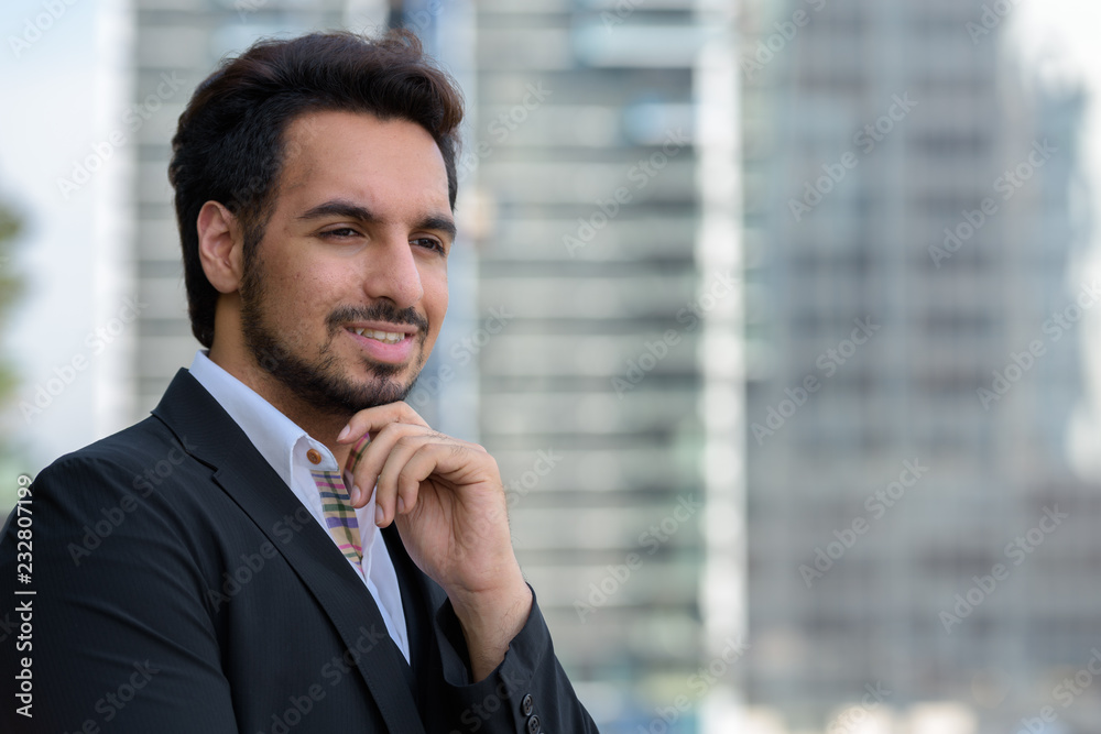 Young happy Indian businessman smiling and thinking at rooftop i Young happy Indian businessman smiling and thinking at rooftop i