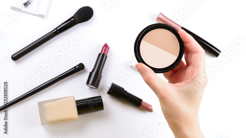 Make up powder in woman hands. Professional makeup products with cosmetic beauty products, foundation, lipstick, eye shadows, eye lashes, brushes and tools.