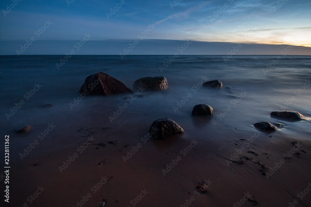 Fototapeta premium long exposure sea beach with rocks and washed out waves of water