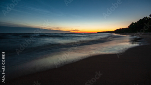 long exposure sea beach with rocks and washed out waves of water