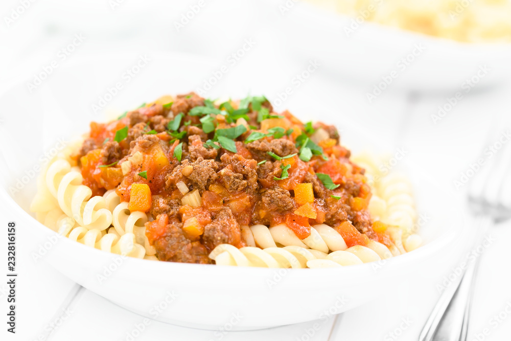 Homemade vegan bolognese sauce made with soy meat, fresh tomatoes, onion and garlic served on fusilli pasta and sprinkled with parsley (Selective Focus, Focus in the middle of the image) Homemade vegan bolognese sauce made with soy meat, fresh tomatoes, onion and garlic served on fusilli pasta and sprinkled with parsley (Selective Focus, Focus in the middle of the image)