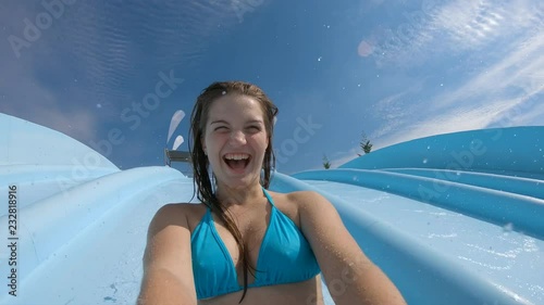 Teenage girl filming herself going down on a waterslide and having fun in slow motion