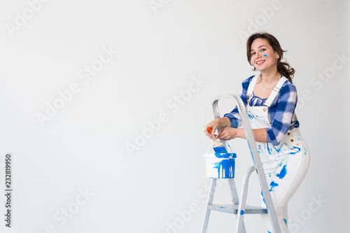 Repair, renovation, worker and people concept - Beautiful woman standing on the ladder and mixing paint over white background with copy space