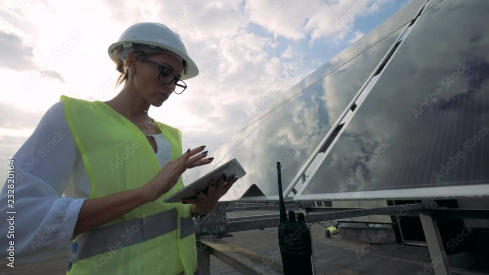 Glasslike solar installation and a lady inspector working near it