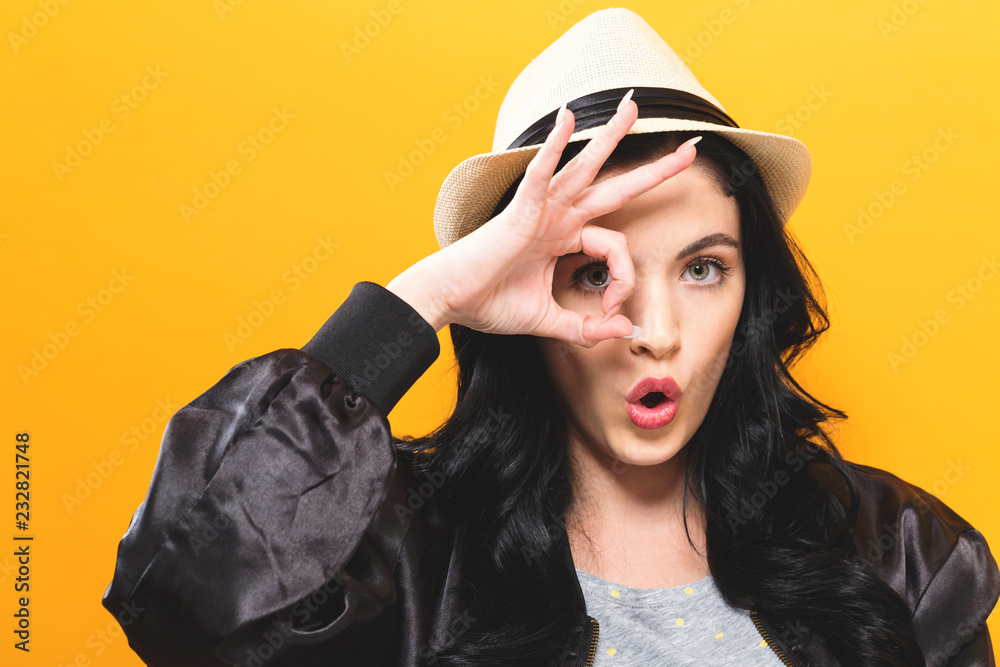 Young woman with ok gesture on a yellow background Young woman with ok gesture on a yellow background