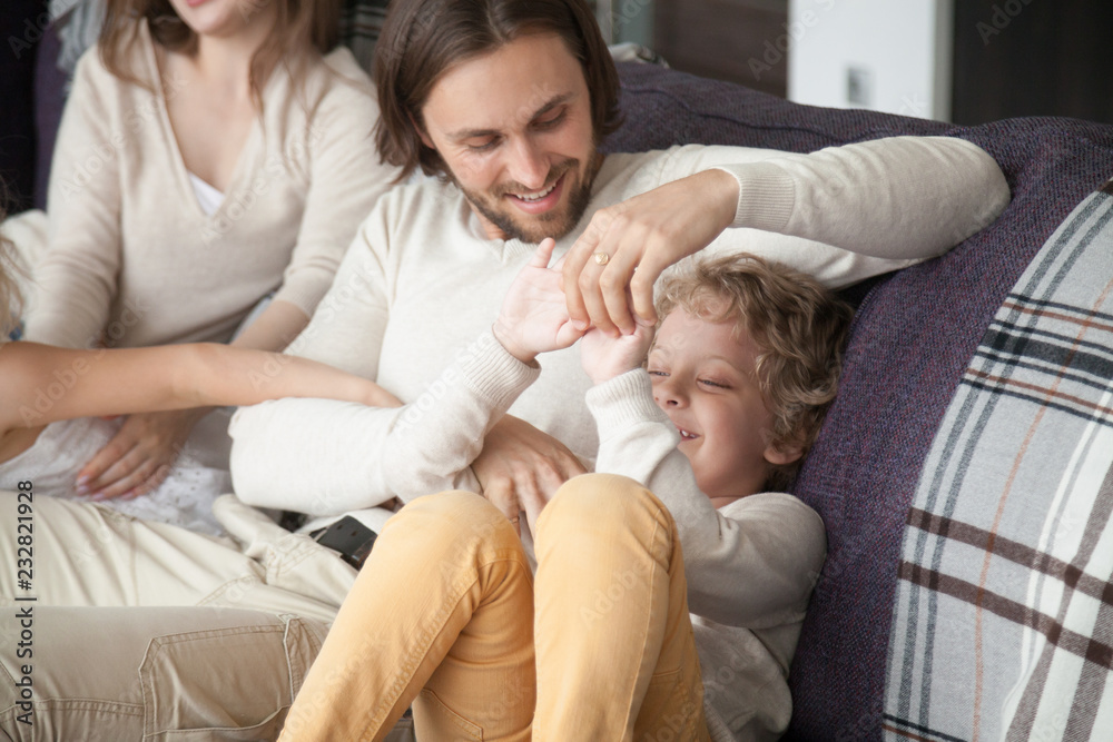 Young married couple with little preschool children playing sitting on couch in living room at new home. Parents and kids having a fun, close up. Happy family, buying real estate and mortgage concept Young married couple with little preschool children playing sitting on couch in living room at new home. Parents and kids having a fun, close up. Happy family, buying real estate and mortgage concept