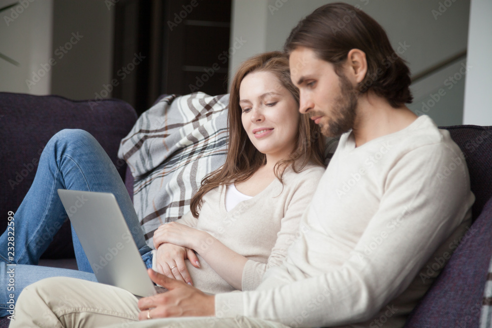 Married couple sitting together on couch in living room at home. Husband and wife using computer, customer shopping purchase online, buy ticket or paying money via internet, e-banking service concept Married couple sitting together on couch in living room at home. Husband and wife using computer, customer shopping purchase online, buy ticket or paying money via internet, e-banking service concept