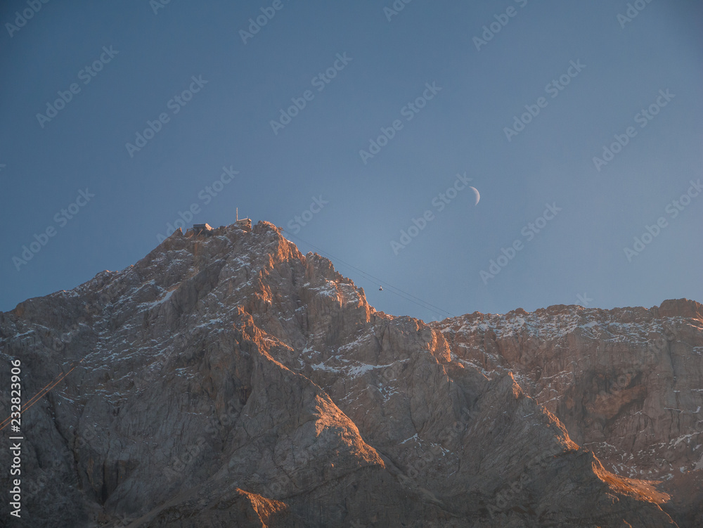 Close up Image of the Zugspitze Germany's highest mountain with moon and gondola