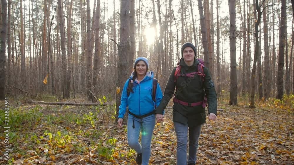 Hiking and Backpacking concept. Young Couple of travelers walking in forest in autumn day Hiking and Backpacking concept. Young Couple of travelers walking in forest in autumn day