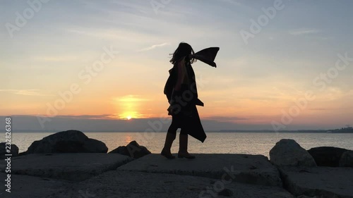 Beautiful girl is dancing at the rocks sunset sea background