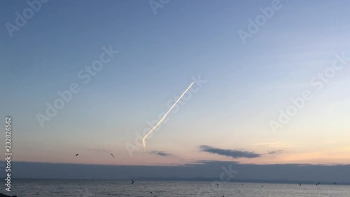Aircraft flying up at the sunset sky above the sea