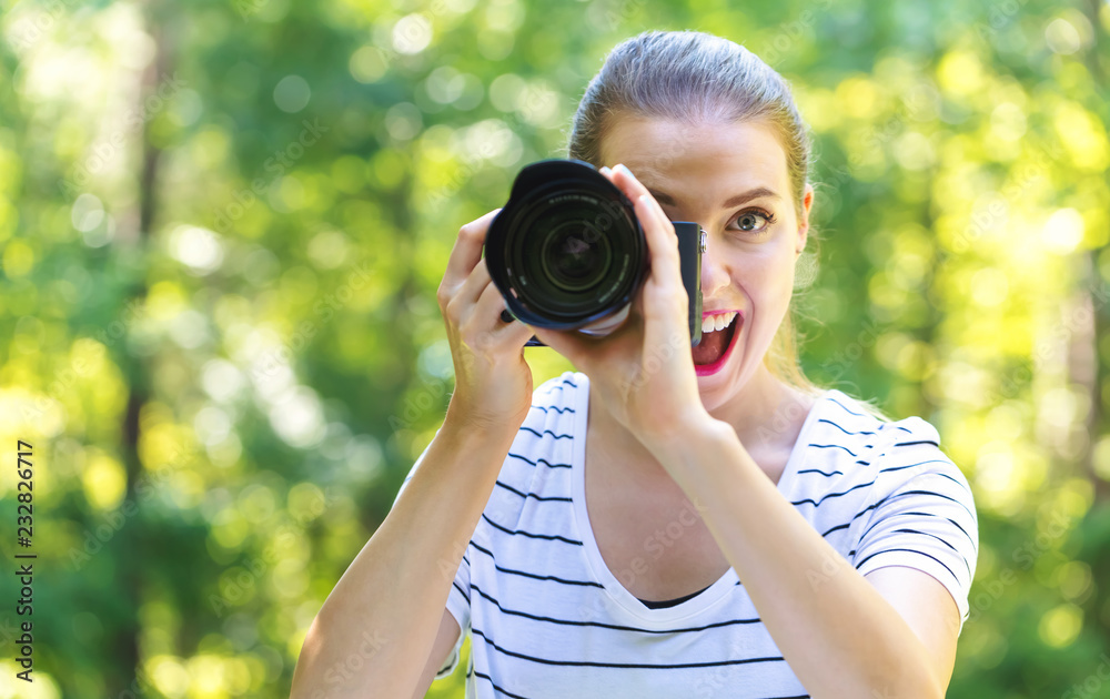 Young woman with a professional digital SLR camera on a bright summer day in the forest Young woman with a professional digital SLR camera on a bright summer day in the forest
