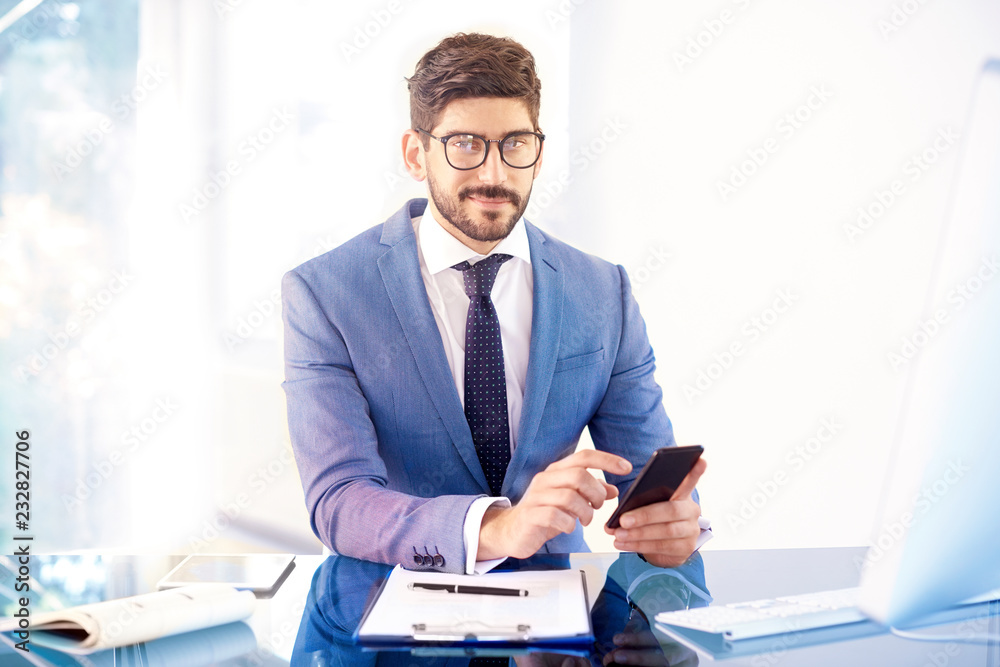 Businessman sitting in the office and text messaging Businessman sitting in the office and text messaging
