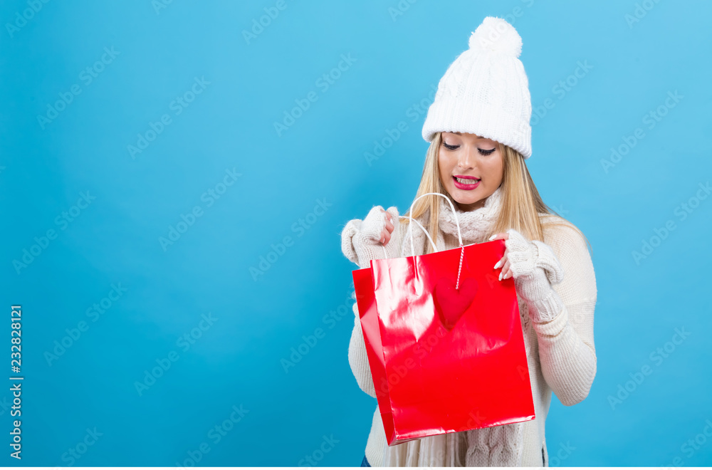 Obraz premium Happy young woman holding a shopping bag on a blue background