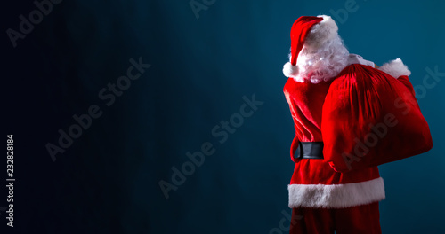 Santa holding a red sack on a dark blue background
