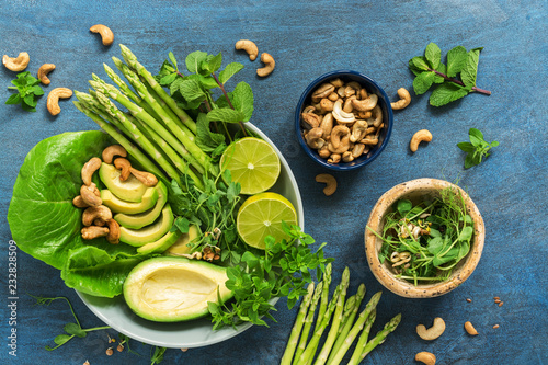 Avocado, asparagus, micro greens, lime, mint,basil, lettuce and cashew nuts. Detox bowl buddha. Blue rustic background, top view. Clean, wholesome food.