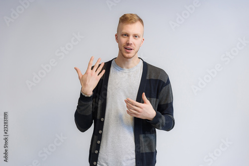 Studio portrait concept of a smiling young man talking on a white background.