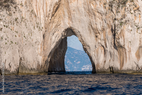 Iconic sea stacks and arch off the coast of Capri, Italy. They are named Stella, Faraglione di Mezzo with the arch, and Fraglione di Furori.
