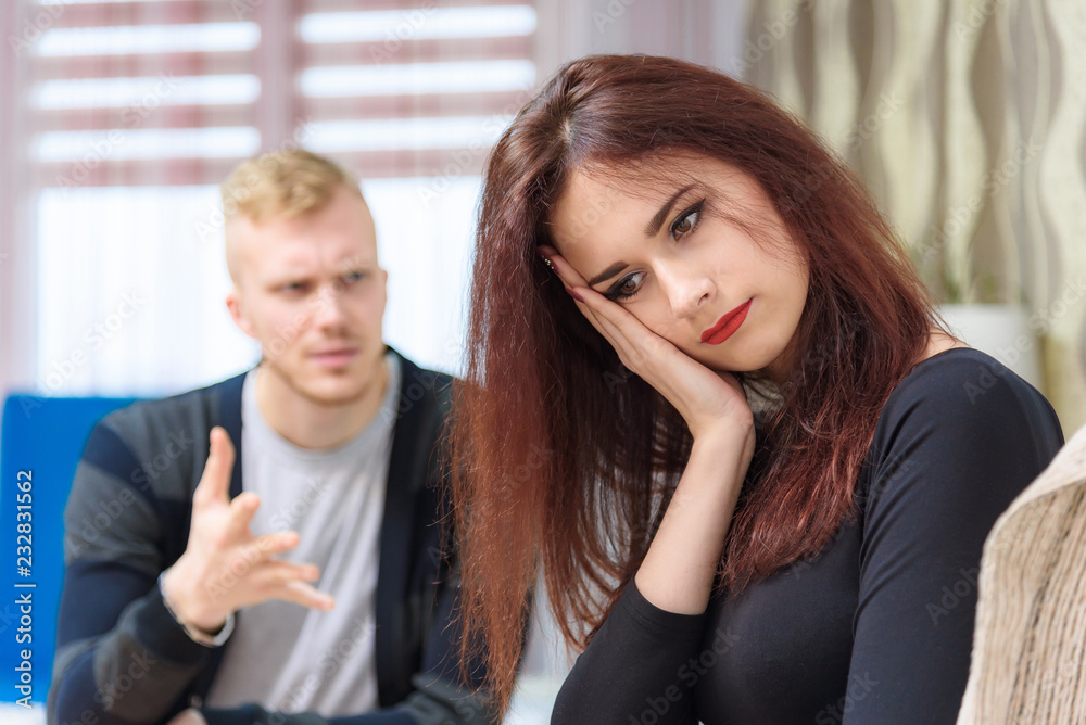 The concept of family conflict, problems, relationships of young disgruntled husband and wife in a room on the sofa. The concept of family conflict, problems, relationships of young disgruntled husband and wife in a room on the sofa.