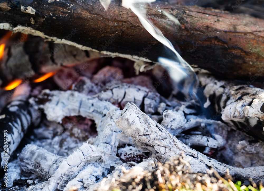 Smoldering embers of fire with log in smoke, close up Smoldering embers of fire with log in smoke, close up