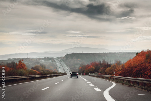 Driving in the mountains on a cloudy moody day with traffic and colorful autumn tree forest. Okertal, Oker gorge, Oker National Park Harz, Harz Mountains, Germany