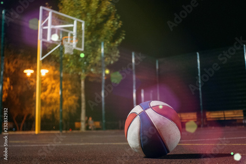 Colorfull basketball ball with basket and net on background on dusk red field with light glowing