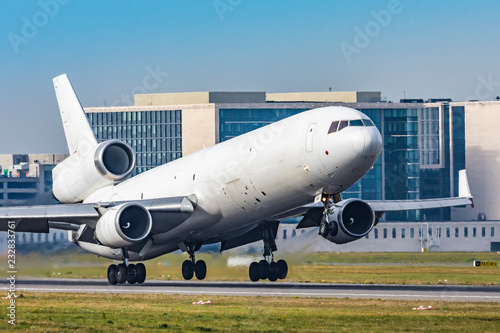 White MD-11 taking off, airport buidlings in the background