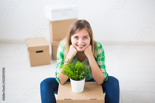 Relocation, new home and real estate concept - Young woman upacking in new flat photo