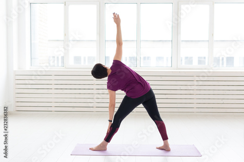 Yoga, harmony, people concept - a middle-aged woman is practicing the yoga and looking in the window