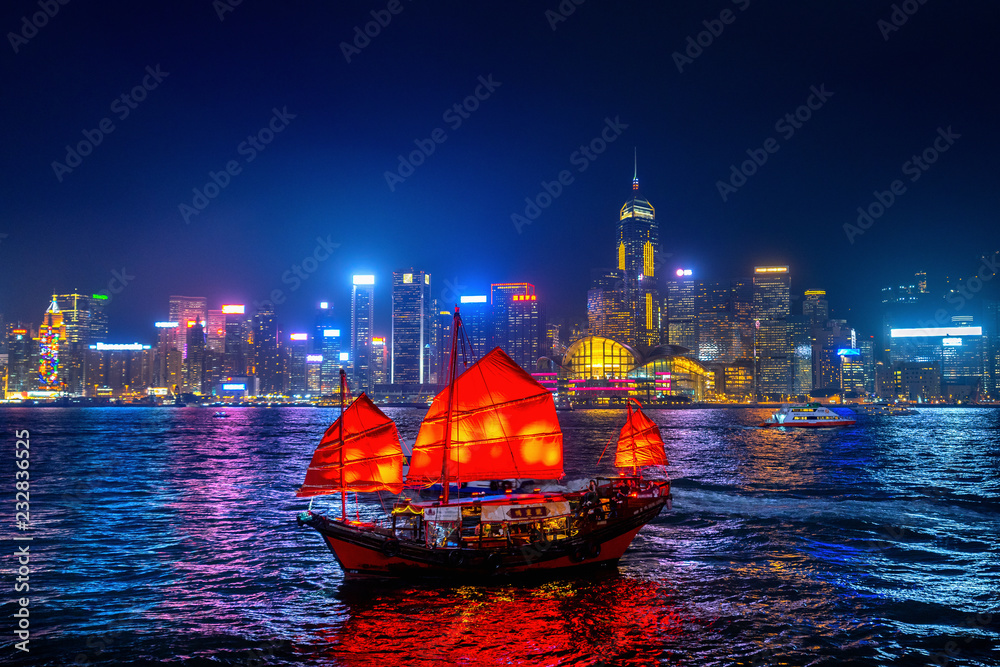 Victoria Harbour with junk ship at night in Hong Kong.