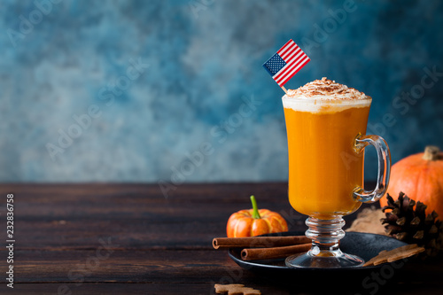Pumpkin spice latte with whipped cream. American flag on top. Wooden background. Copy space.