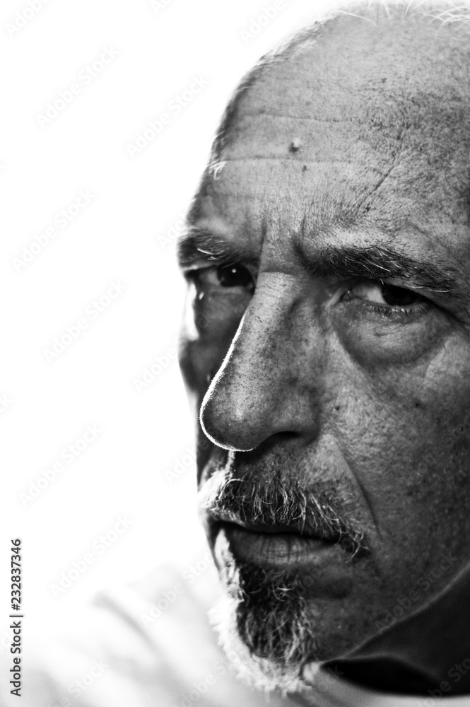 Back lit three quarter portrait of man looking at viewer with serious expression. Shallow depth of field.