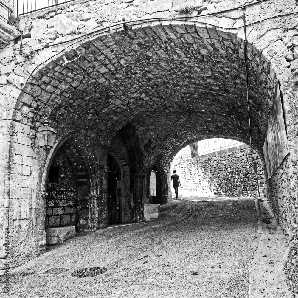 Fototapeta premium Figure walking away through and old archway