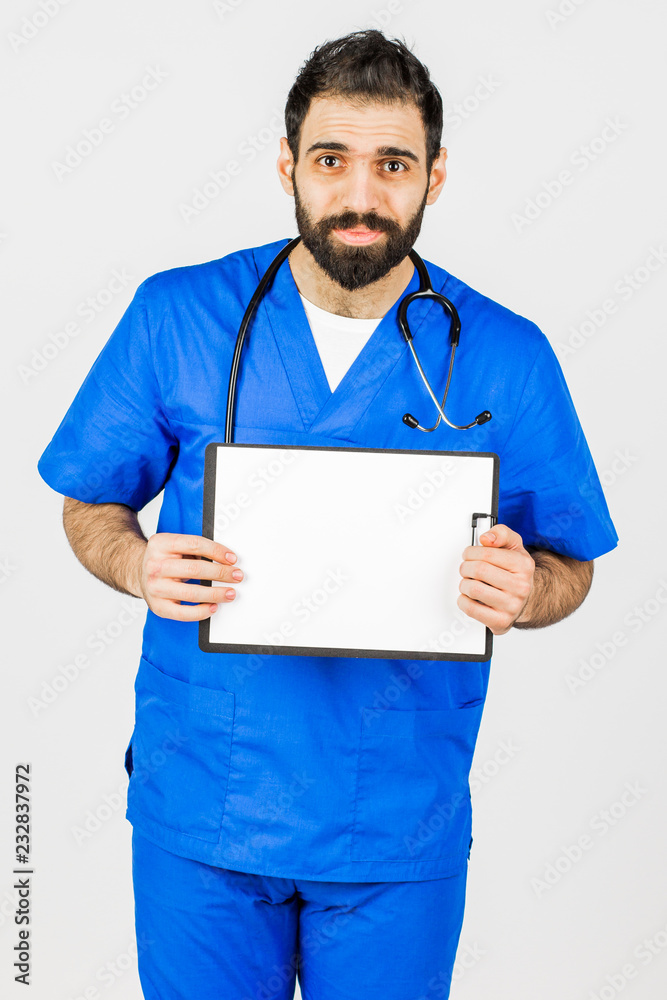 Doctor in blue robe with stethoscope pointing to clipboard isolated on white background Doctor in blue robe with stethoscope pointing to clipboard isolated on white background