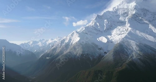 Slow drone aerial pan up right to reveal of Annapurna II mountain peak and snow face in high altitude Himalayan landscape seen from 4000m elevation at Ghyaru village, Nepal. 4k 1.9:1 23.976fps photo